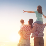 "A family of four, with the parents carrying their children on their shoulders, watching the sunset together. Text on the left reads 'You're not just another face... you are family.'"
